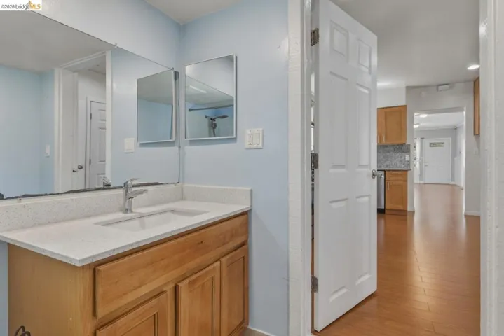 Bathroom vanity featuring a light wood-finish cabinet, integrated sink, and a light-toned countertop