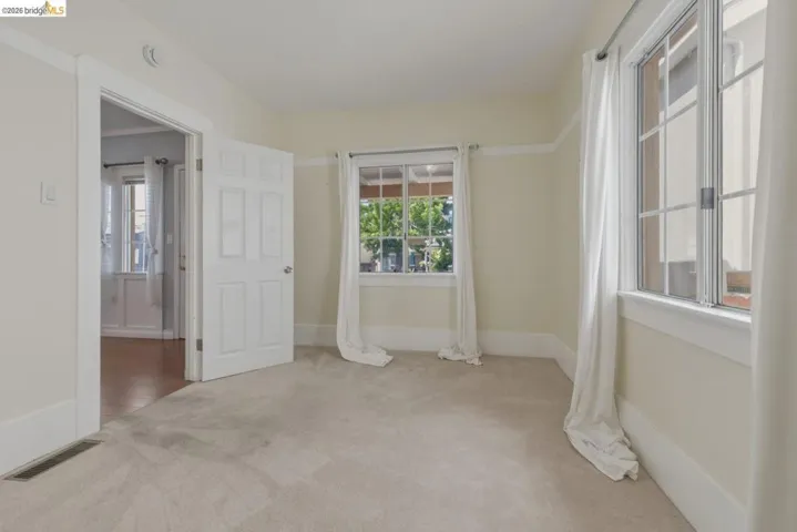 Carpeted room featuring multiple windows with trim, a six-panel door, and painted walls
