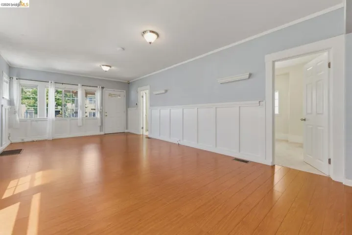 Spacious room featuring rich wood-finish flooring and extensive wainscoting