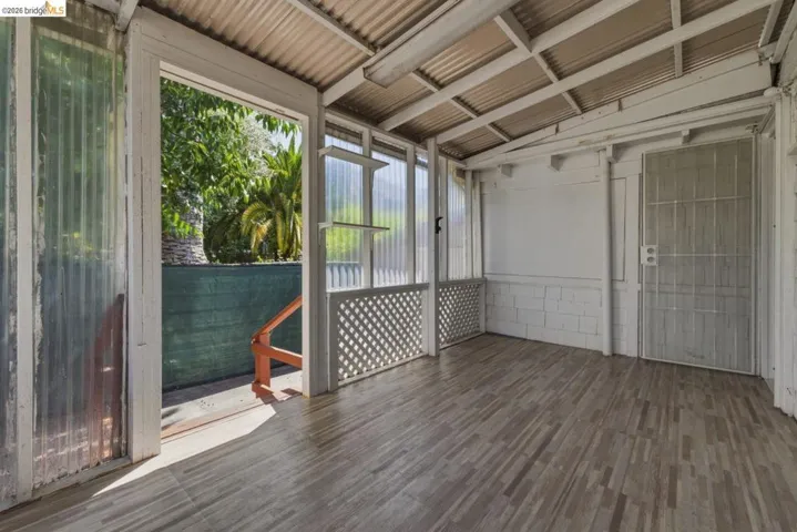 Screened porch featuring wood-finish flooring, a corrugated metal roof, and lattice accents