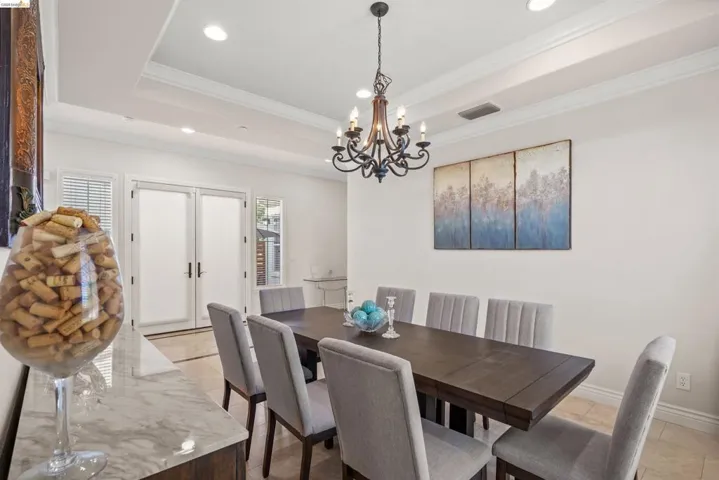 Dining area featuring a dark wood finish table, upholstered chairs, and a tray ceiling