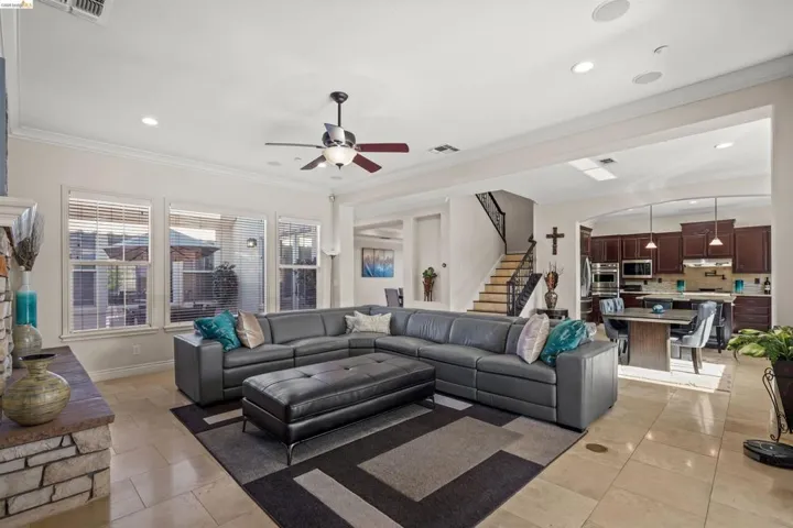 Spacious living area featuring stone-clad fireplace, recessed lighting, and crown molding