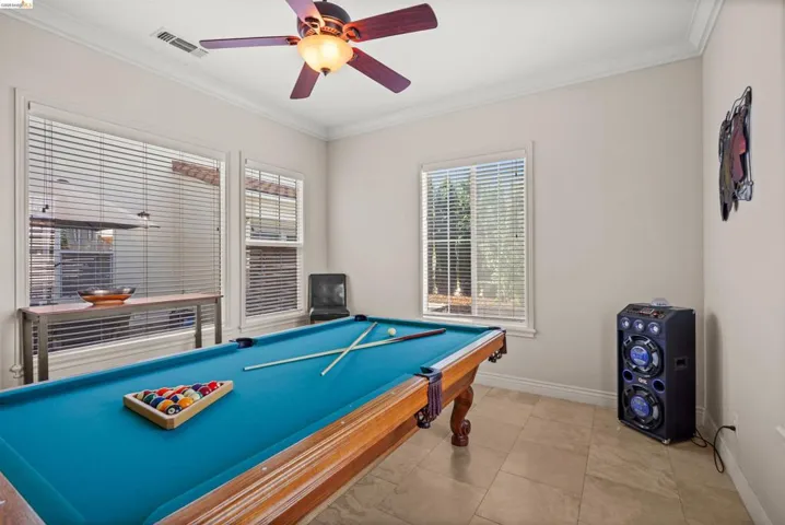 Versatile bonus room featuring tile flooring, crown molding, and multiple windows with blinds for controlled natural light