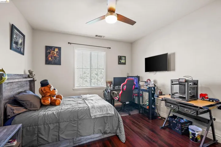 Room featuring wood-finish flooring, a window with blinds, and a ceiling fan with integrated lighting