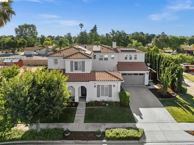 Stucco exterior with a tile roof, an arched entry, a two-car garage, and a concrete driveway