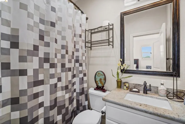 Bathroom vanity featuring a granite countertop, white undermount sink, and matte black faucet