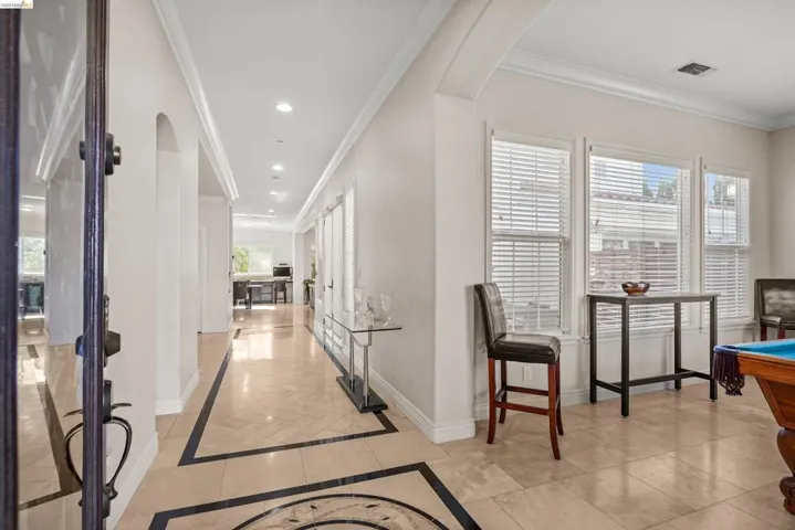 Spacious entryway featuring light-toned tile flooring with dark accent borders, recessed lighting, and crown molding