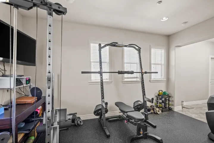 Dedicated fitness space featuring rubberized flooring, recessed lighting, and two windows with blinds