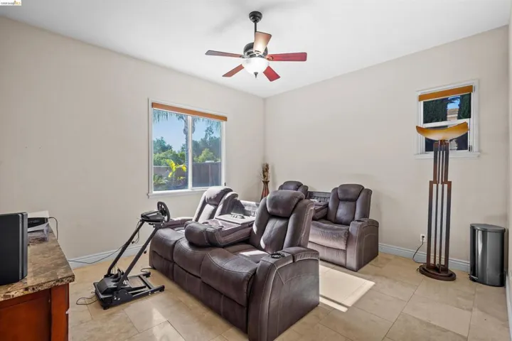 Spacious room with large windows, tile flooring, a ceiling fan, and ample wall space