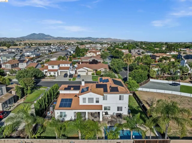 Two-story residence featuring a terracotta-style tile roof and multiple solar panel arrays