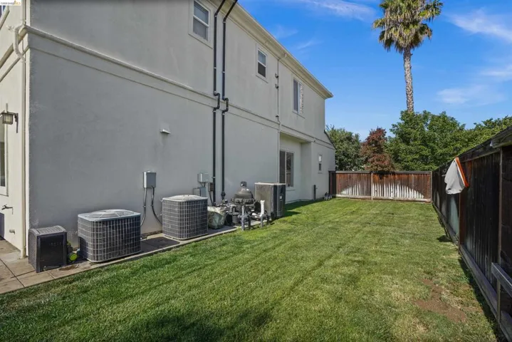 Spacious backyard featuring a manicured lawn, a wood fence, and a palm tree backdrop