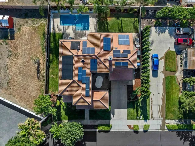 Property featuring a tile roof, solar panels, a paved driveway, and a backyard swimming pool