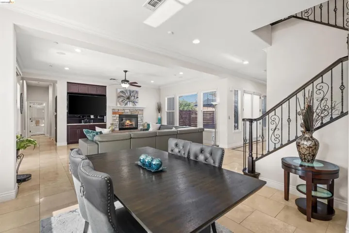 Open-concept dining and living areas featuring neutral-toned tile flooring, recessed lighting, and crown molding