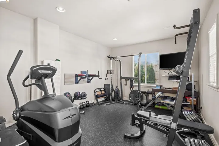 Dedicated fitness space featuring rubber flooring, recessed lighting, and multiple windows with blinds