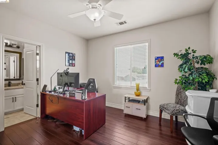 Room featuring dark wood-finish flooring, a ceiling fan with integrated lighting, a window with horizontal blinds, and light-toned wall paint