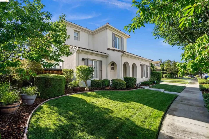 Two-story stucco exterior featuring arched entryways, prominent window shutters, and a tile roof