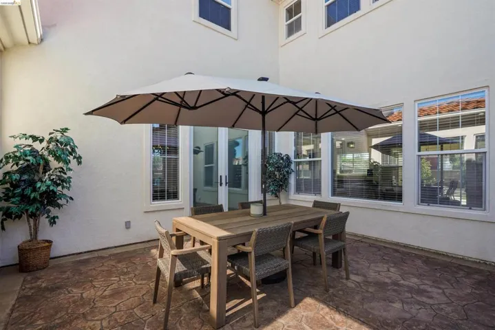 Expansive stamped concrete patio with multiple windows and a glass slider for abundant natural light