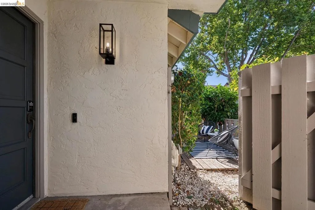 Entryway featuring paneled door, black lantern-style wall sconce, and textured stucco exterior