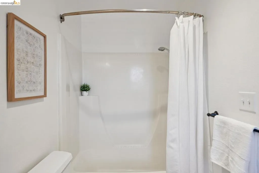Shower-tub combination featuring a curved shower rod and integrated shelving