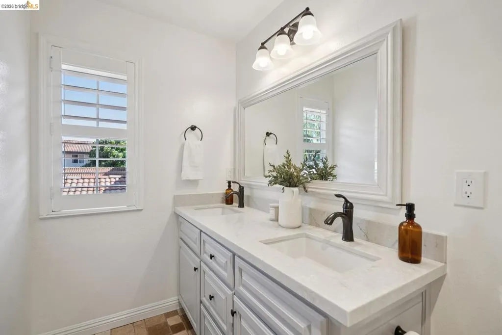Dual-sink vanity with light gray cabinetry and integrated sinks set in a light-toned countertop