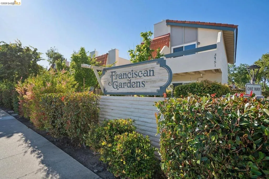 Entryway sign framed by dense, green shrubbery
