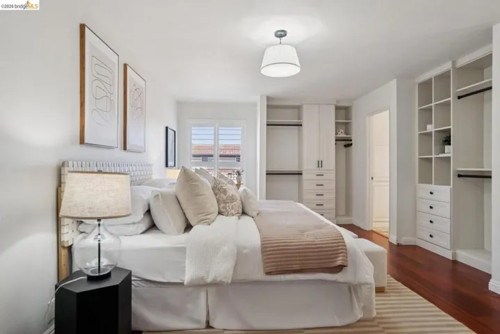 Bedroom featuring rich wood-finish flooring, white walls, and a ceiling light fixture