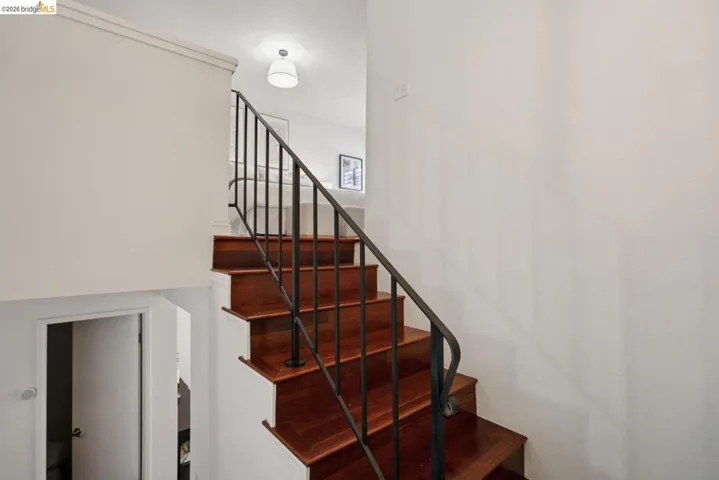 Hardwood staircase featuring dark wood-finish treads and risers, complemented by a black metal balustrade and handrail