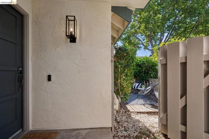 Entryway featuring paneled door, black lantern-style wall sconce, and textured stucco exterior