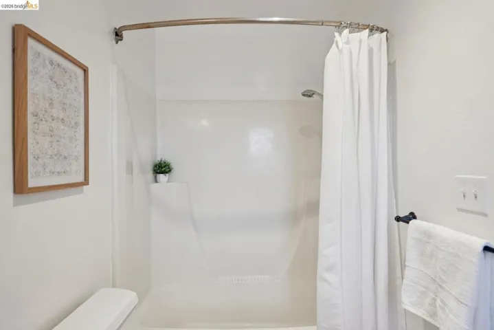 Shower-tub combination featuring a curved shower rod and integrated shelving