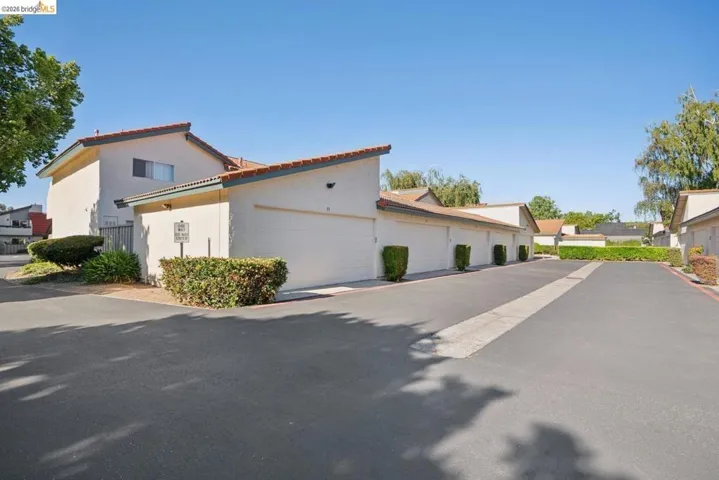 Residential complex with stucco exterior, terra cotta roof tiles, and individual garage access