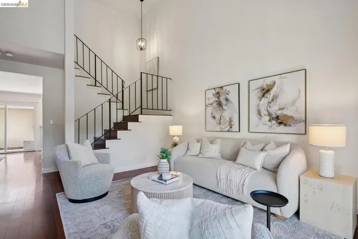 Two-story living area featuring high ceilings, dark wood-finish flooring, and a modern open staircase with black metal railings