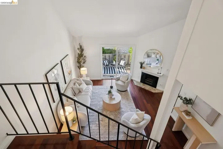 Living area with high vaulted ceilings, wood-finish flooring, and a fireplace with a stone hearth