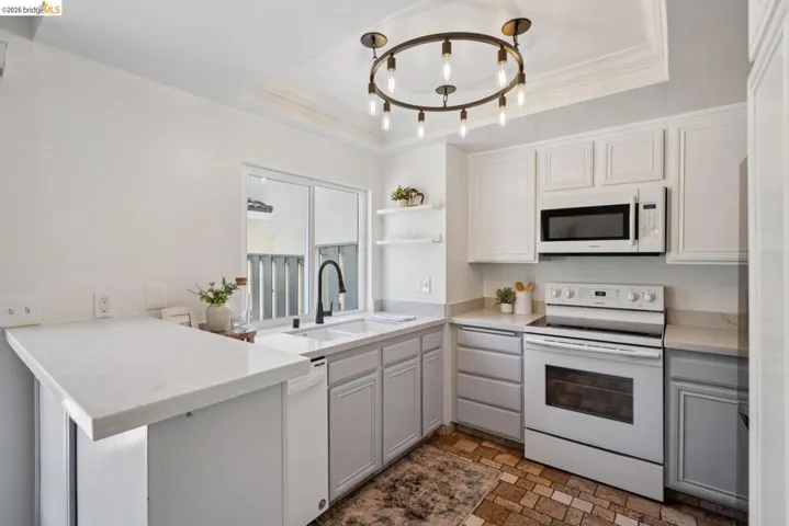 Kitchen featuring white upper cabinetry, light grey lower cabinetry, and light-toned countertops