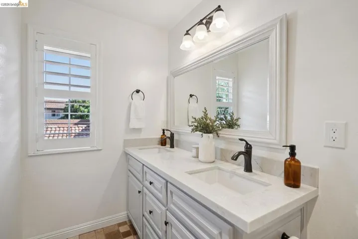 Dual-sink vanity with light gray cabinetry and integrated sinks set in a light-toned countertop