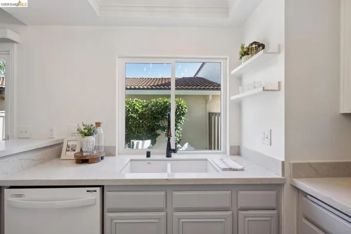 Kitchen featuring a double basin sink, light blue paneled cabinetry, and light-toned countertops