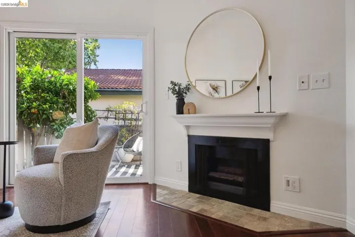 Living area featuring a fireplace with a white mantel, dark wood-finish flooring, and sliding glass doors opening to an outdoor patio with striped paving