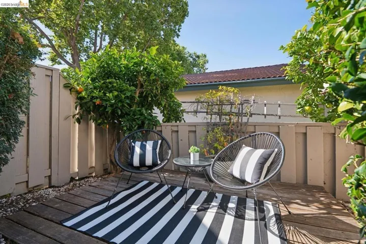 Private outdoor patio featuring wood decking, a privacy fence, and mature citrus trees