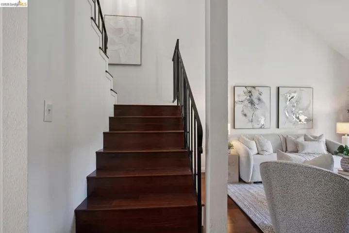 Wood-finish staircase with black metal railing and white risers