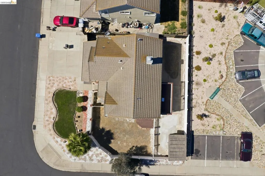 Corner lot property featuring a tiled roof, concrete driveway, and front landscaping with manicured lawn and decorative stones