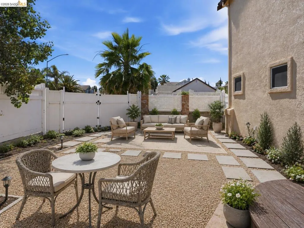 Expansive outdoor living area featuring a gravel ground cover, large square stepping stones, and surrounding planted beds