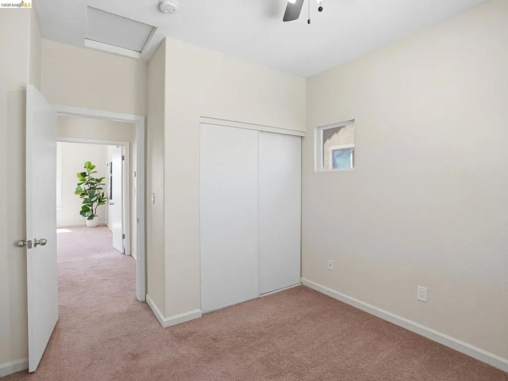 Room featuring neutral wall tones, textured carpet flooring, and a ceiling fan