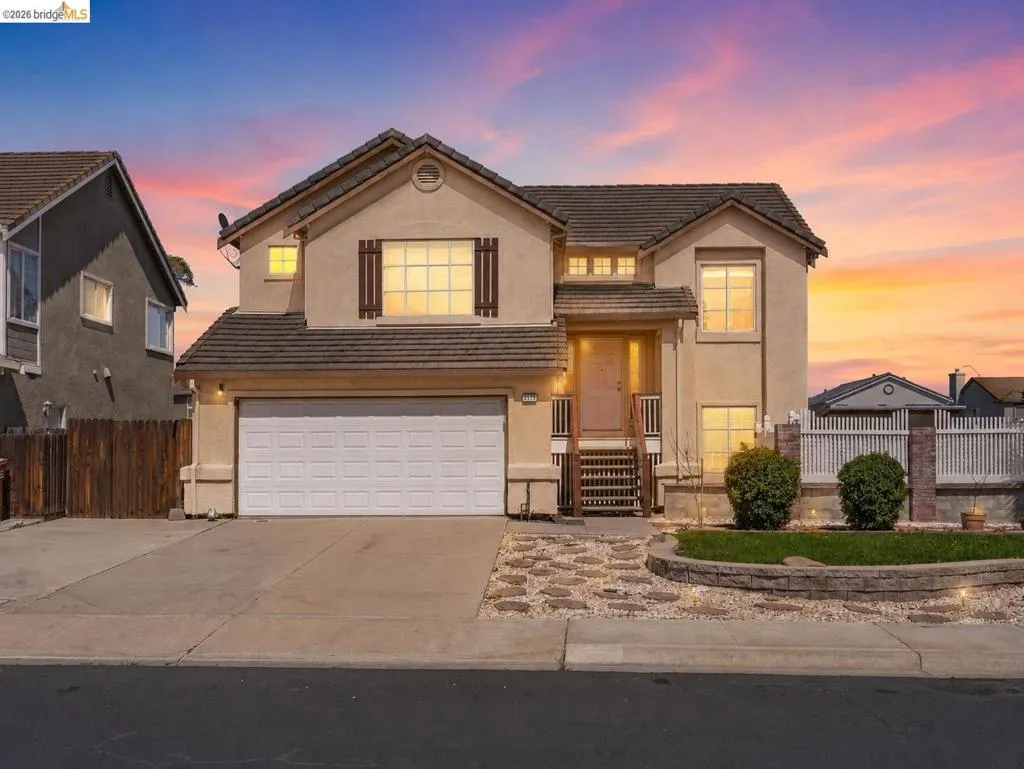 Two-story stucco residence featuring a tile roof and decorative window shutters