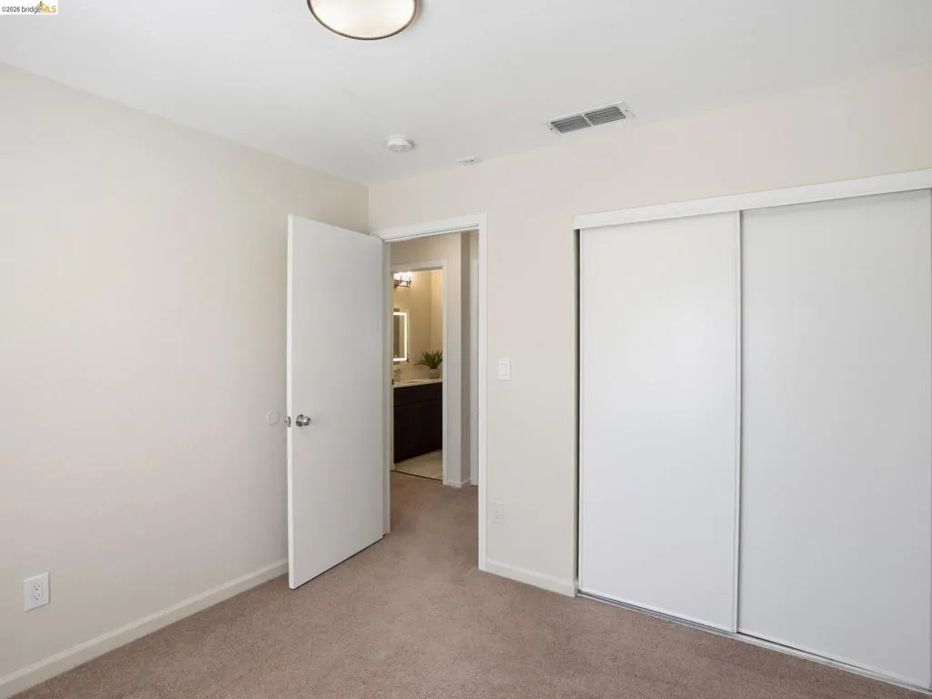 Bedroom featuring neutral carpeting, white interior doors, and a built-in closet with sliding doors