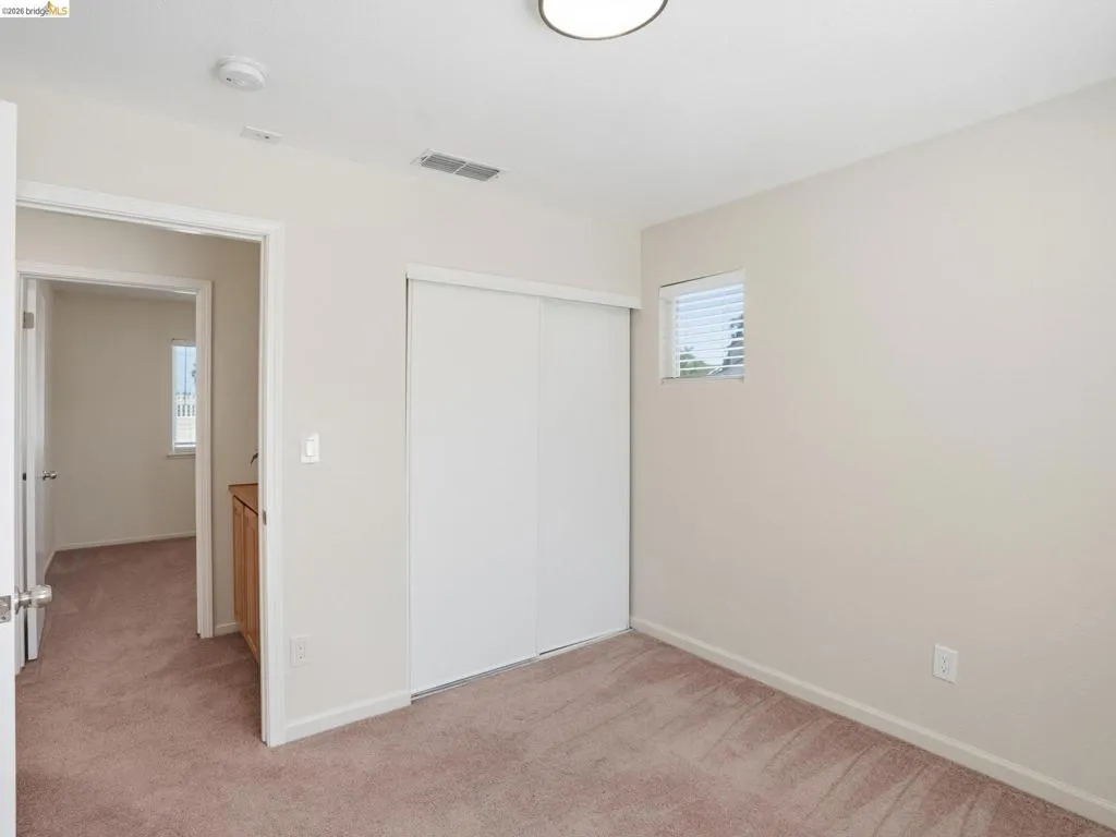 Carpeted room featuring a window with horizontal blinds, a white bi-fold closet, and a flush-mount ceiling light fixture