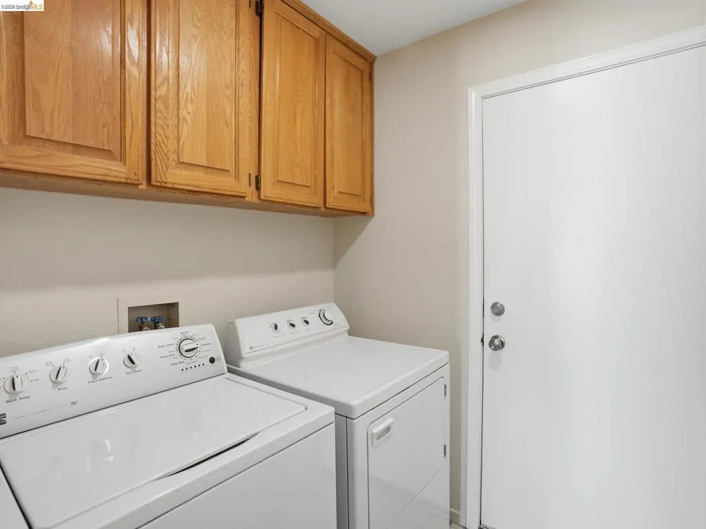 Utility area featuring overhead wood cabinetry and a white door with brushed nickel hardware