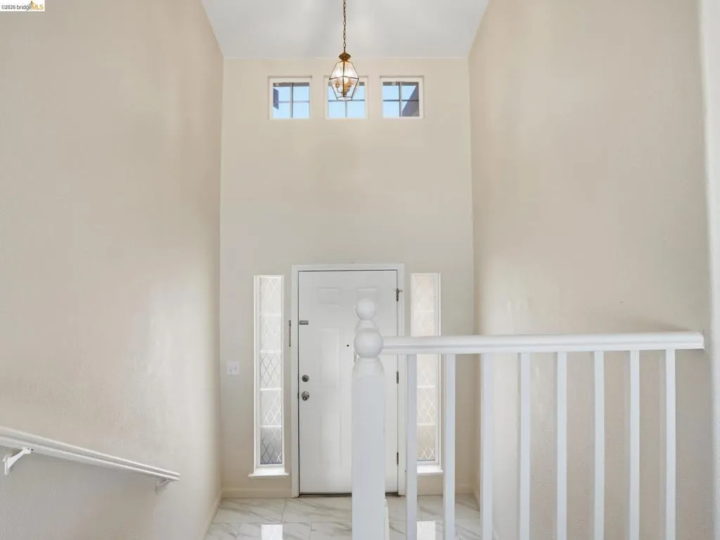 Entryway featuring a high ceiling, a decorative pendant light fixture, and three transom windows