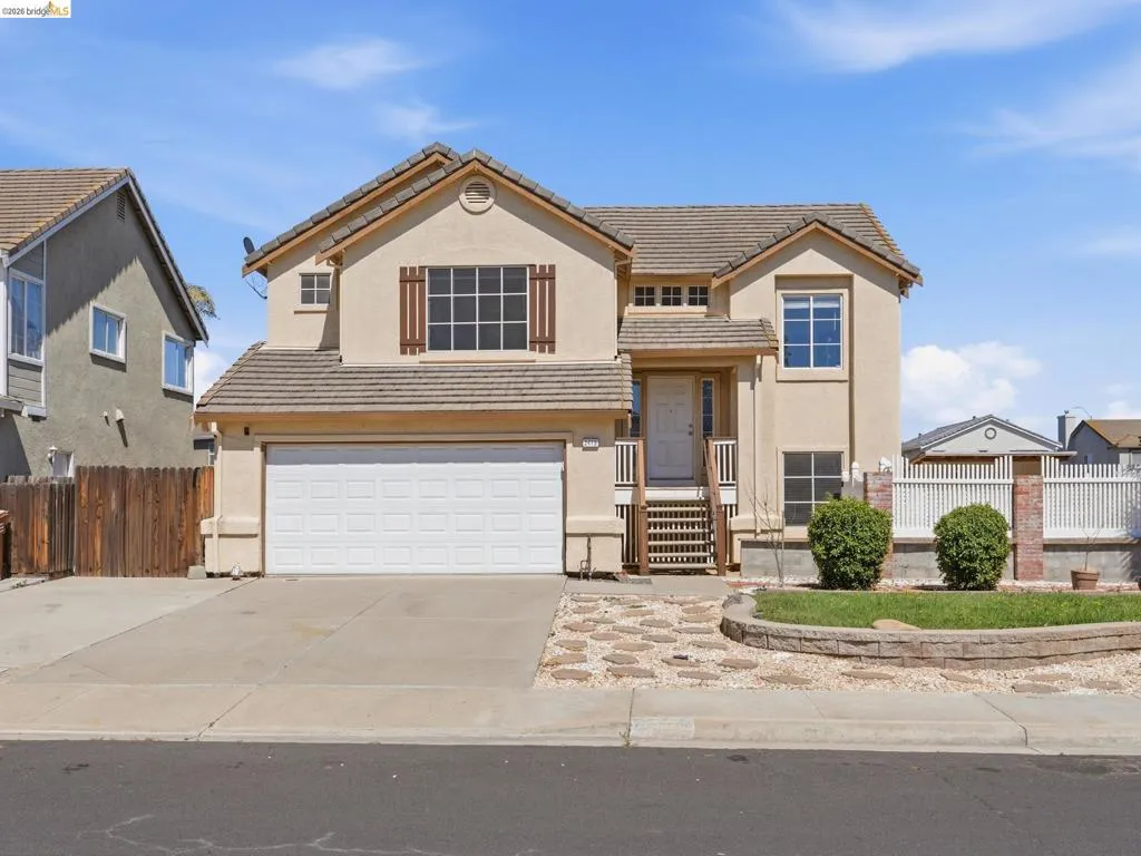 Two-story residence featuring a neutral stucco exterior and a tiled roof