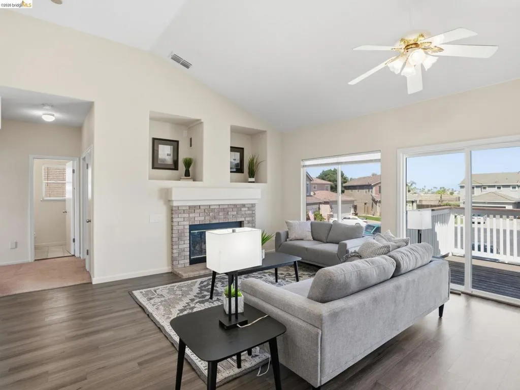 Living area featuring vaulted ceilings, wood-finish flooring, and a stone-surround fireplace with built-in display niches