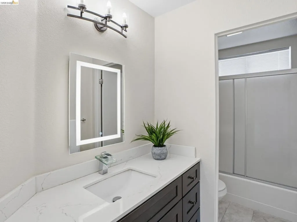 Bathroom vanity featuring a rectangular undermount sink, a white quartz countertop, and a dark wood-finish cabinet