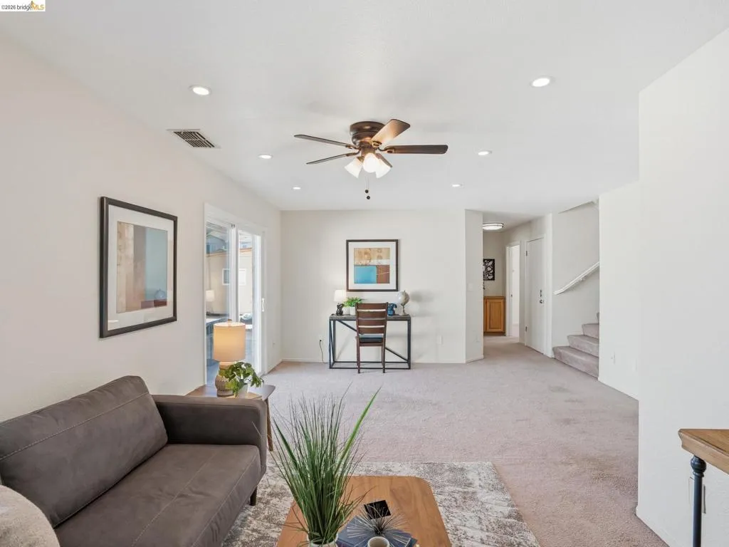 Open-concept living area with neutral carpeting and light wall tones